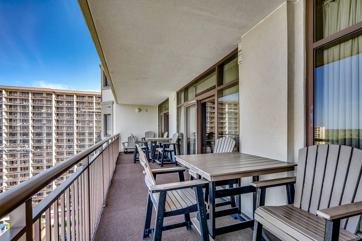 This image captures a private balcony furnished for comfort, with glass railings offering a clear, panoramic view of the surrounding area. The setting invites relaxation, suggesting moments spent enjoying a sunrise coffee or evening cocktails while taking in scenic vistas.