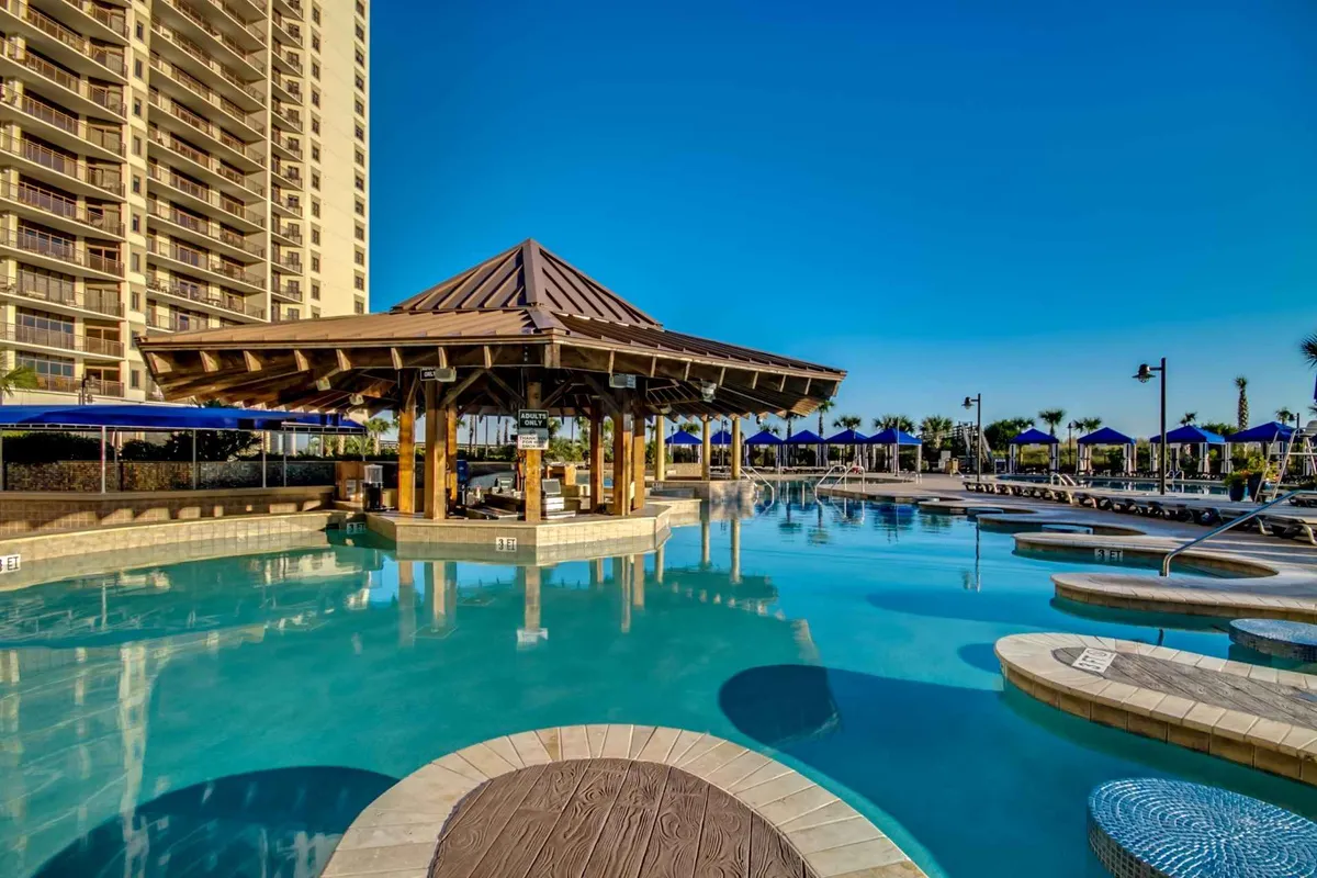 An exterior shot focusing on a pool area with a charming gazebo, plenty of lounge chairs, and people socializing and sunbathing. The soft sunset lighting creates a warm and inviting mood, emphasizing relaxation, fun, and community gatherings by the water.