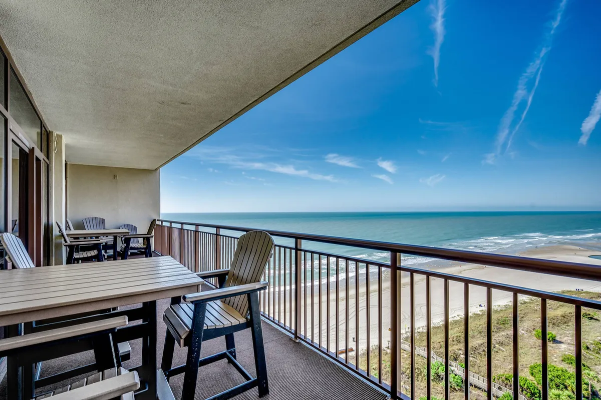 An exterior view from the oceanfront balcony, complete with comfortable seating and a breathtaking view of the beach and skyline. The setup is perfect for savoring a morning coffee or hosting intimate evening gatherings as the sun rises or sets over the water.